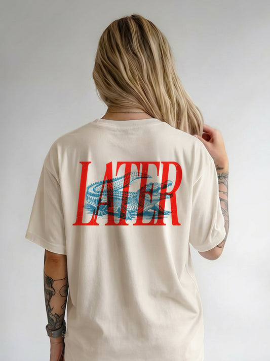 Person wearing a beige t-shirt with 'LATER GATOR' printed on the back against a plain background